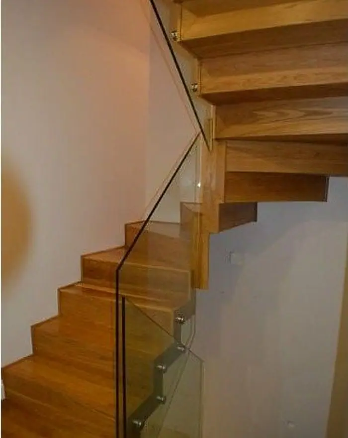 An oak staircase with a frameless glass balustrade, by Ogival